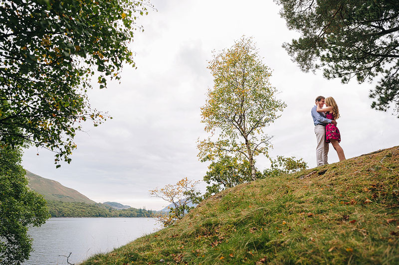 Amazing photograph of a couple hugging between the trees on the brow of a hill