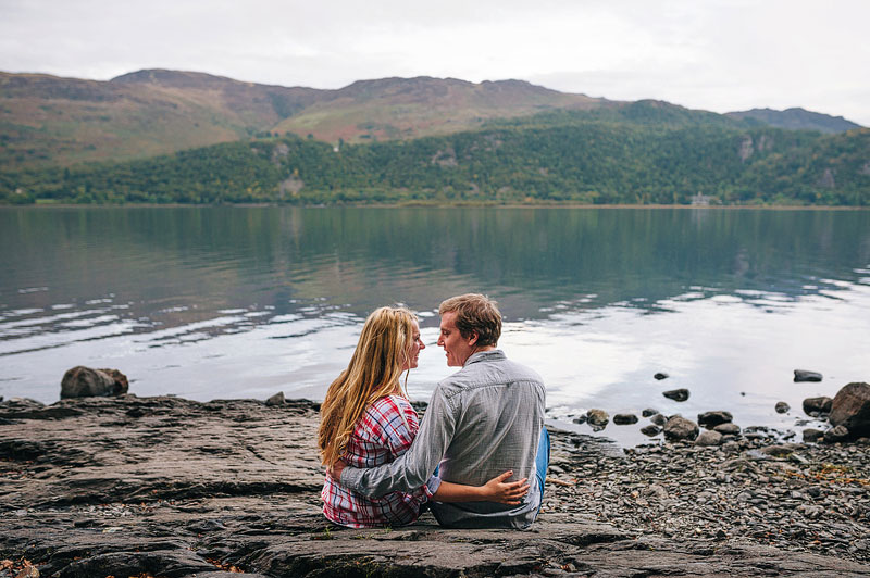 couple sitting on rocky beach, with their arms around each other