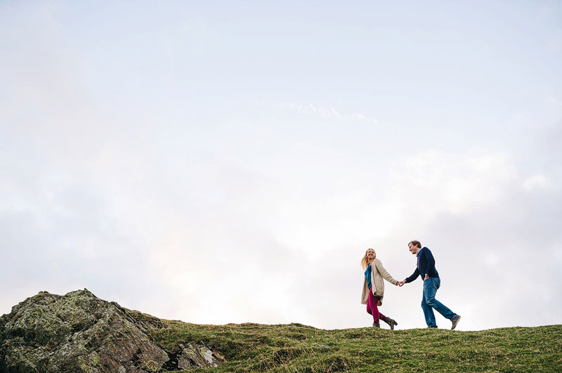 couple walking together hand in hand across a hilltop