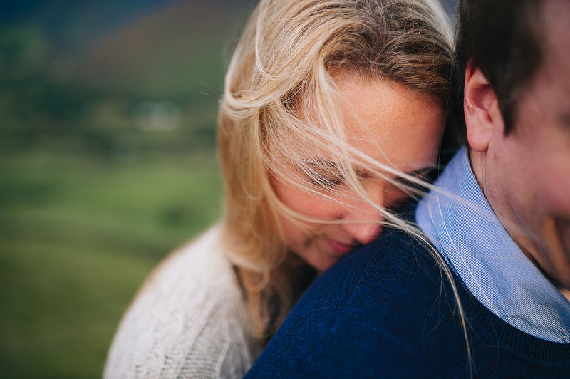 As she hugs her fiancee, a womans hair is swept by the wind beautifully across her face