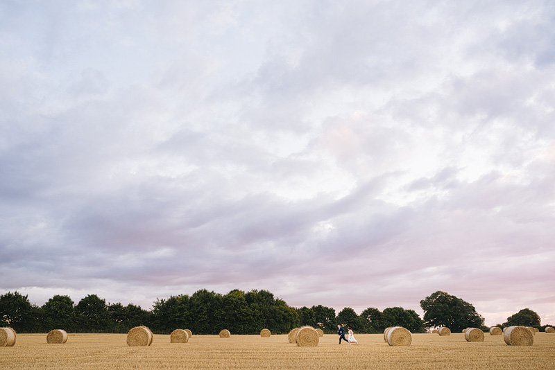 twia winner bride and groom running through hay bales in a cornfield 
