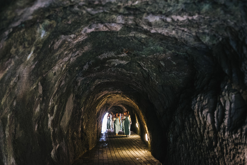 bridesmaids walking through rock tunnels at tunnels beaches