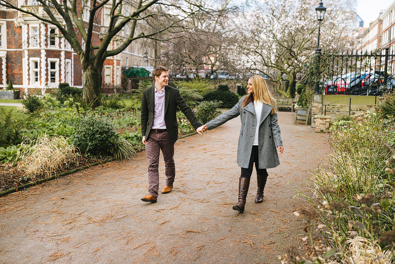 engaged couple hold hands as they walk through temple gardens on the south bank