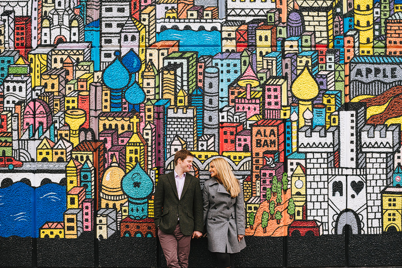 engaged couple standing in front of a cool graffiti wall