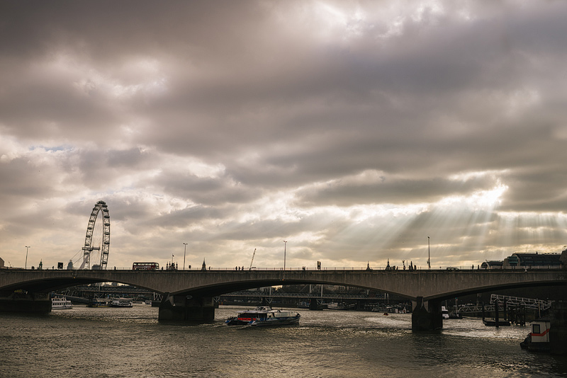 sun shining through clouds over the river thames