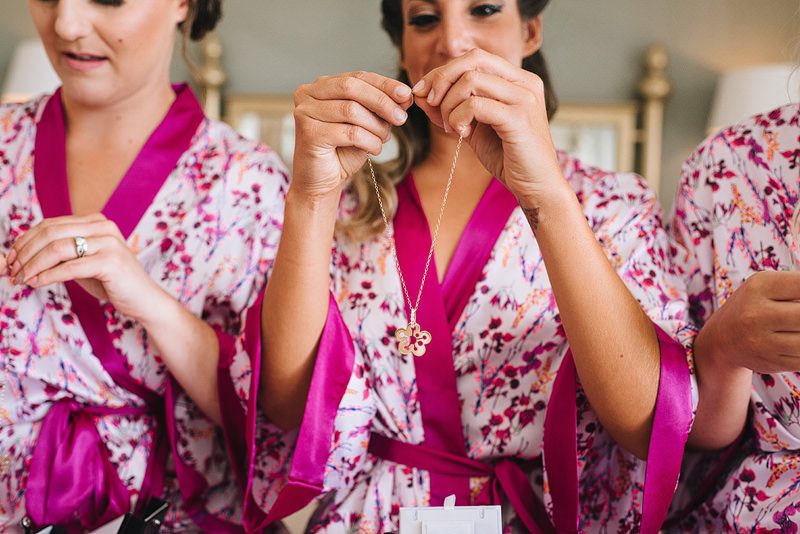 a bridesmaid holds her necklace in her hands