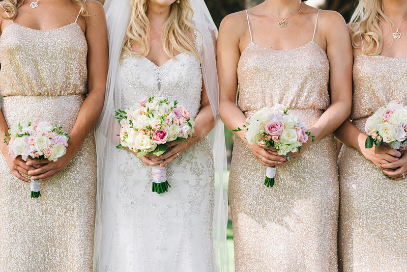 the bridal party holds up their boquets of flowers of yellow, pi