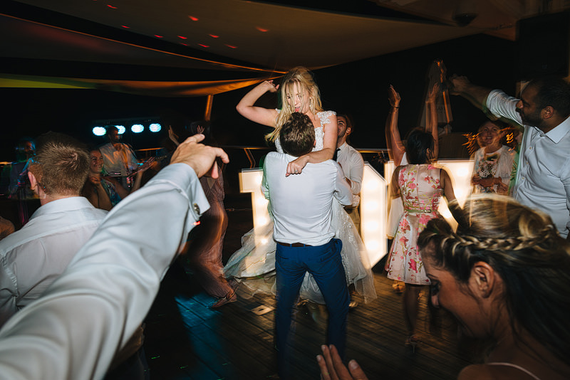 the groom lifts his wife up and spins on the dancefloor
