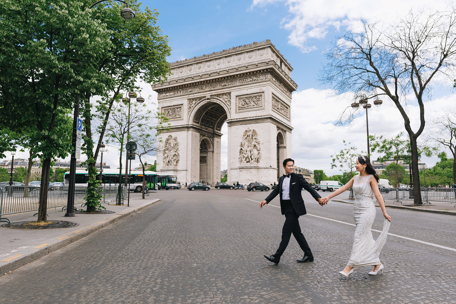 Pre-wedding shoot in Paris. Couple walking past Arc de Triomphe.