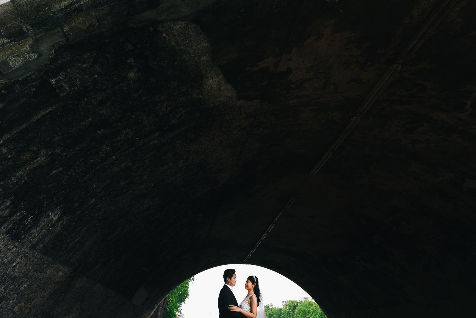 Couple embrace under a bridge during a pre-wedding shoot in Paris