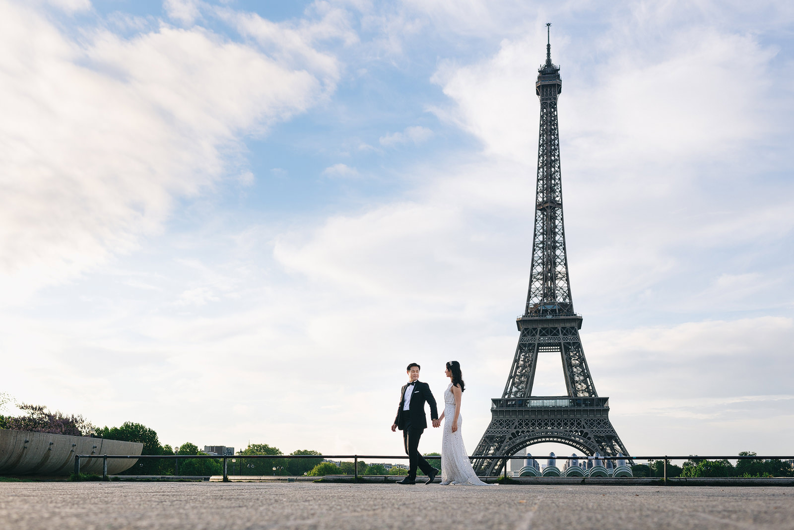 Pre-wedding shoot in Paris. Couple walking past the Eiffel Tower.