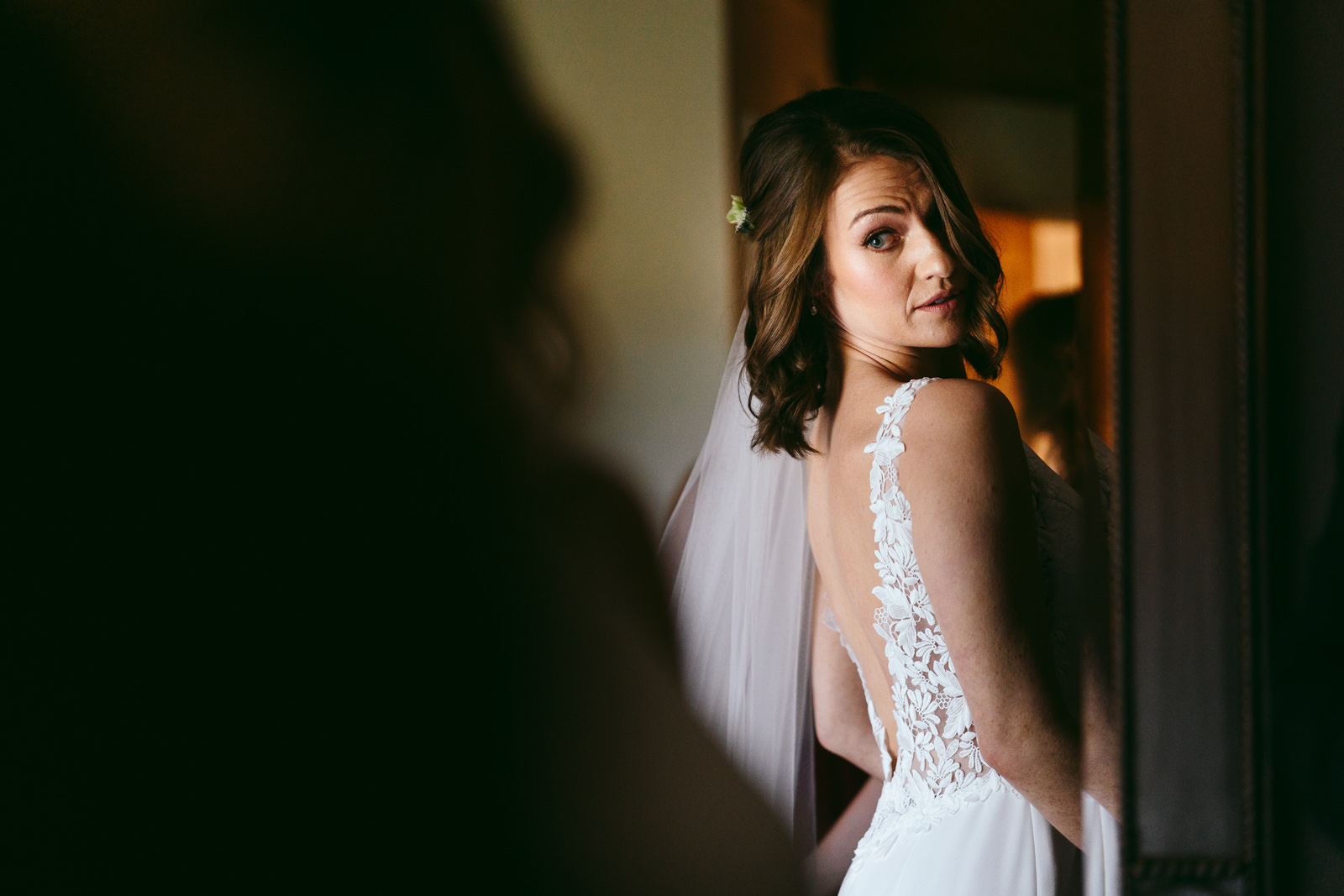 the bride looks at herself in the mirror